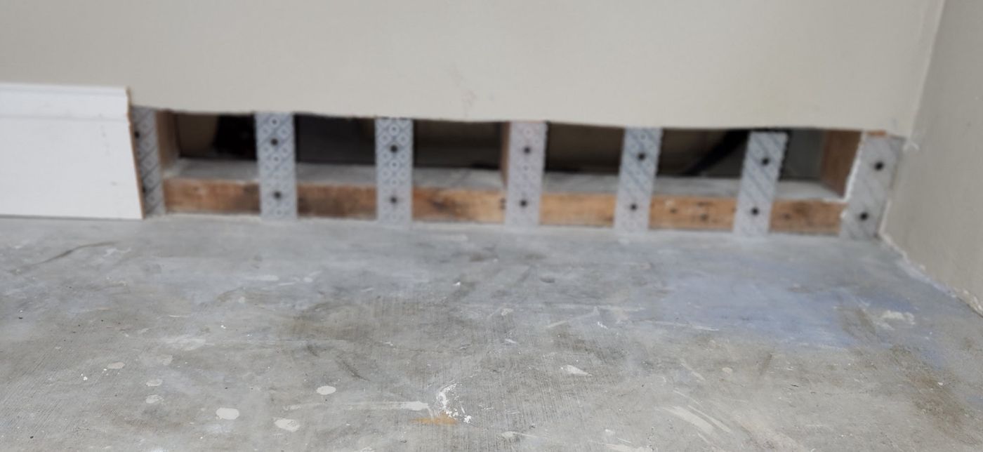 Rock Bloks mounted at each wall stud along the base plate with drywall resting on them and open bays between