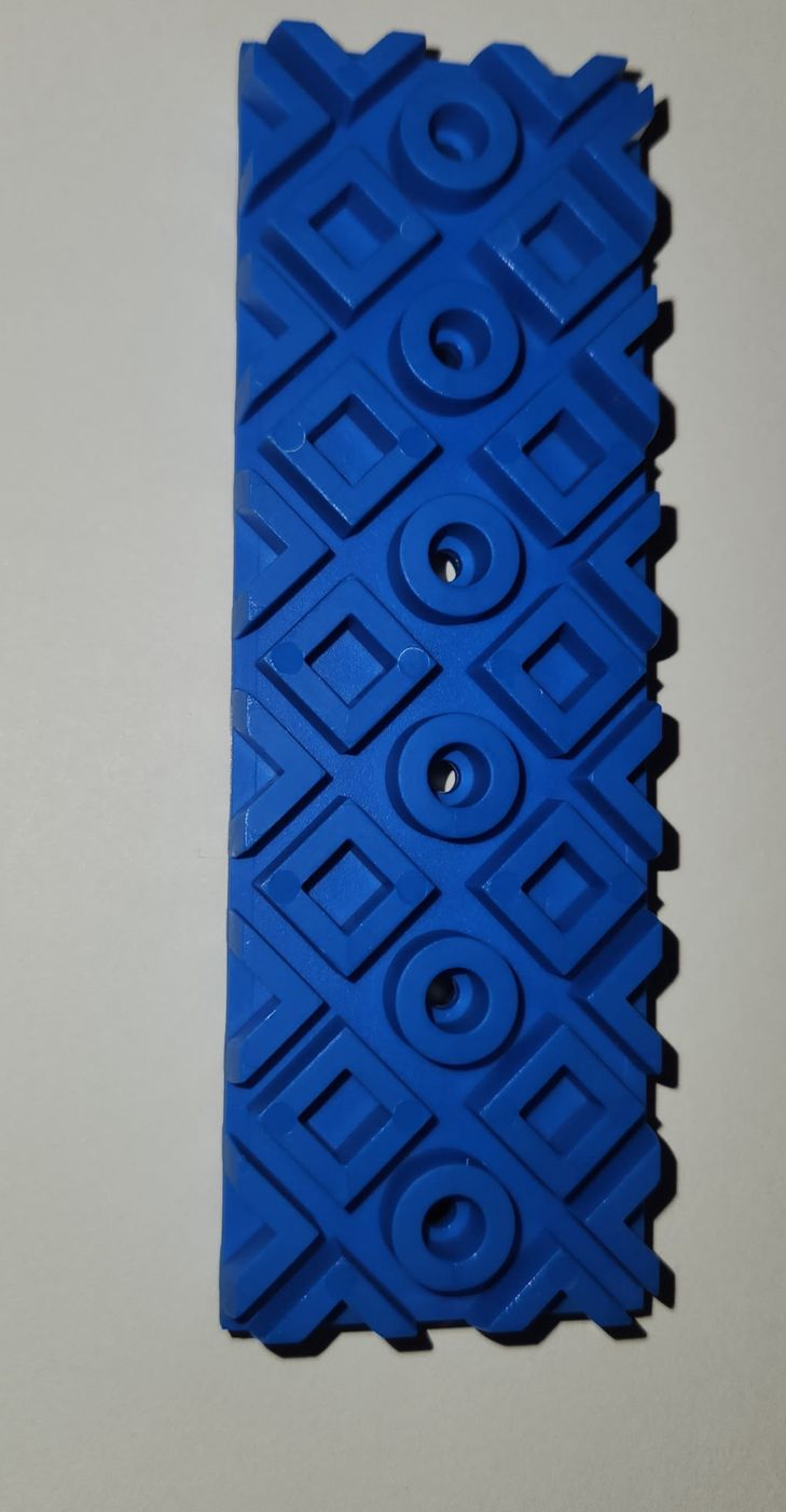Close-up of a blue moulded Rock Blok with a diamond lattice pattern and countersunk screw holes