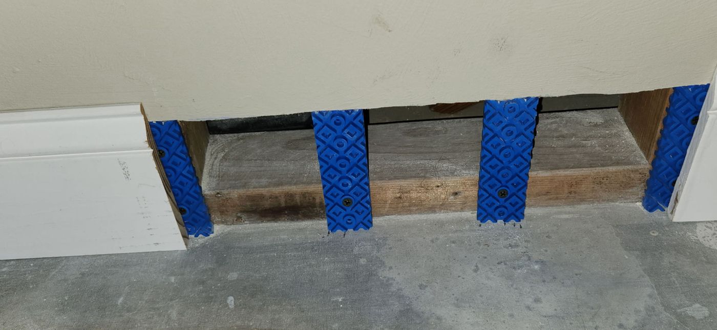 Blue Rock Bloks at each stud with drywall above and an open drainage gap along the base of the wall