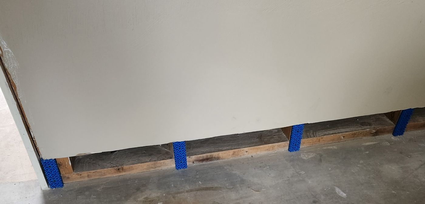 Full wall run with blue Rock Bloks installed at each stud and drywall resting on them