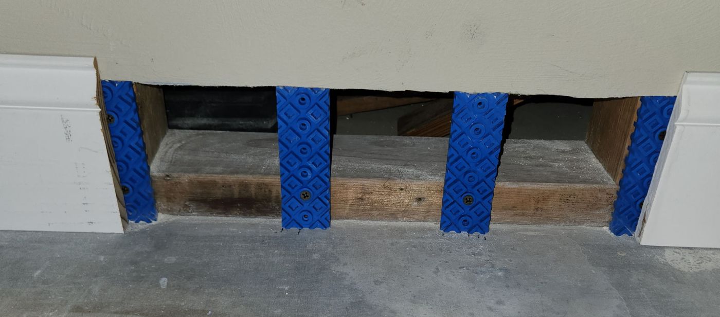 Blue Rock Bloks mounted vertically at each wall stud with drywall resting on top, leaving an open gap at the base of the wall